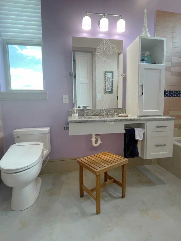 Toilet with bidet seat and vanity with seated bench at sink